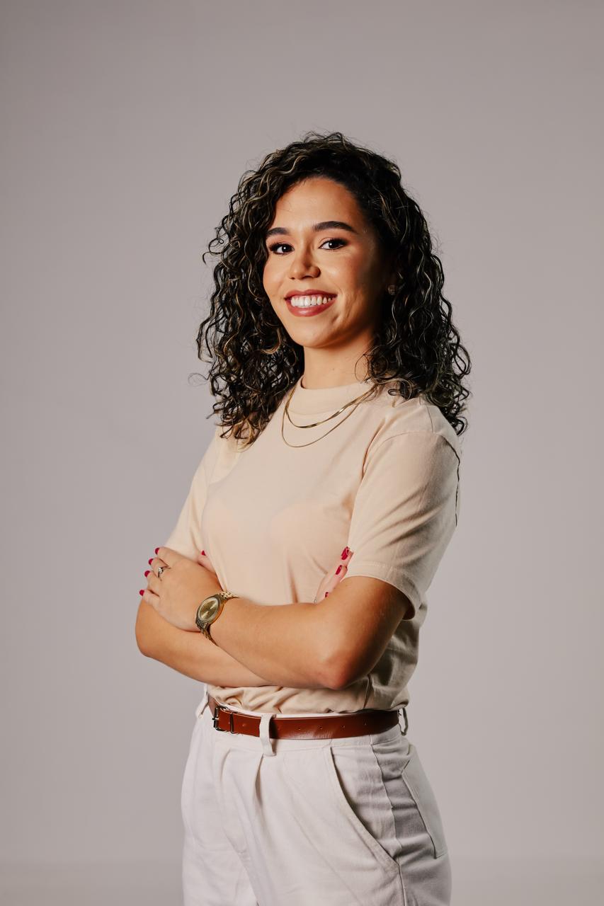 Jessiane Cunha sorrindo, de braços cruzados